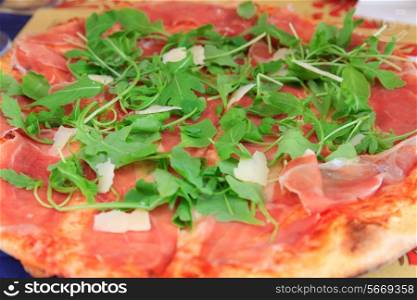 Italian pizza with parmesan, rucola and prosciutto closeup view&#xA;