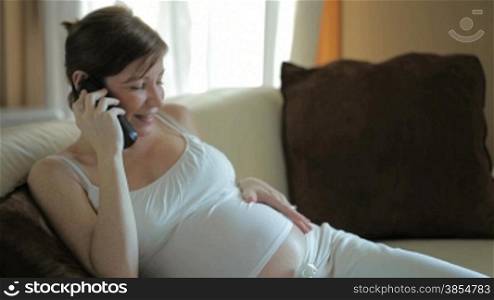 Italian pregnant woman talking on the telephone and sitting on sofa
