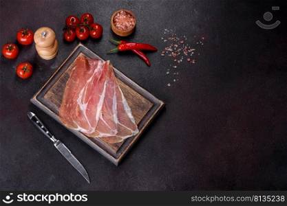 Italian prosciutto crudo or spanish jamon on a dark cutting board with salt and spices. Italian prosciutto crudo or spanish jamon on a dark cutting board