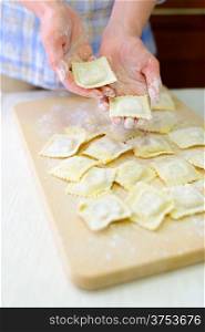 Italian ravioli. Cooking: woman laying out fresh ravioli on a cutting board