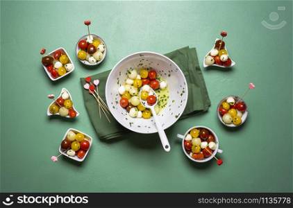 Italian salad with cherry tomatoes, melon and mozzarella balls on green background. Fresh summer salad. Caprese salad portions. Above view of diet food.