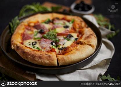 Italian salami pizza with mozzarella and fresh herbs served on plate.. Italian salami pizza with mozzarella
