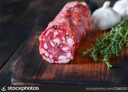 Italian salami with fresh thyme on the wooden board