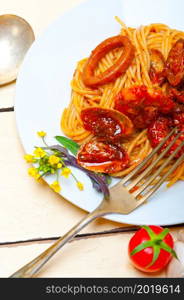 Italian seafood spaghetti pasta on red tomato sauce over white rustic wood table