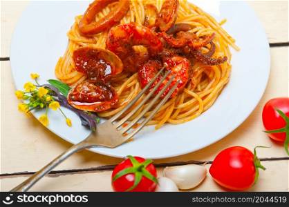 Italian seafood spaghetti pasta on red tomato sauce over white rustic wood table