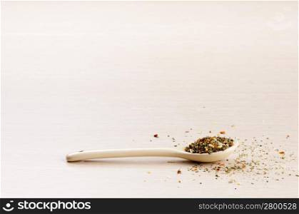 Italian Seasoning in a spoon with some spilt over the wooden background
