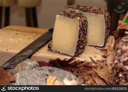 Italian Sheep&rsquo;s Milk Cheese: Aged Pecorino, Knife, Wooden Cutting Board and Autumnal Dry Leaves