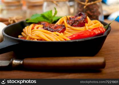 italian spaghetti pasta and tomato with mint leaves on iron skillet over wood board