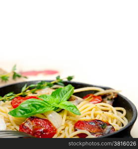 italian spaghetti pasta with baked tomatoes basil and thyme sauce on a cast iron skillet