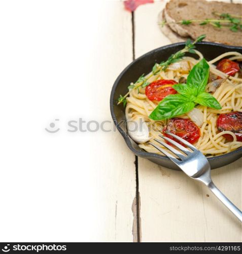 italian spaghetti pasta with baked tomatoes basil and thyme sauce on a cast iron skillet