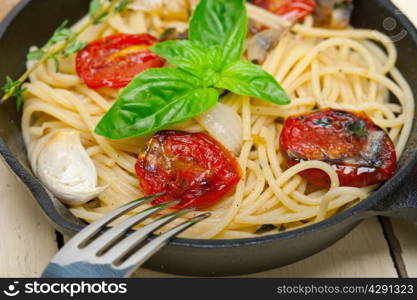 italian spaghetti pasta with baked tomatoes basil and thyme sauce on a cast iron skillet