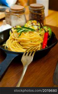 italian spaghetti pasta with zucchini sauce on iron skillet over wood board