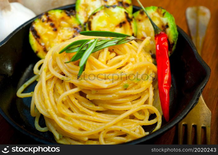 italian spaghetti pasta with zucchini sauce on iron skillet over wood board