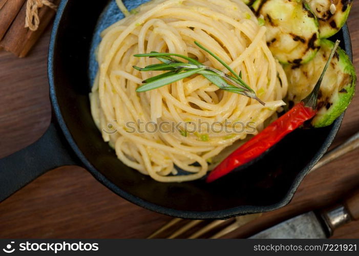 italian spaghetti pasta with zucchini sauce on iron skillet over wood board