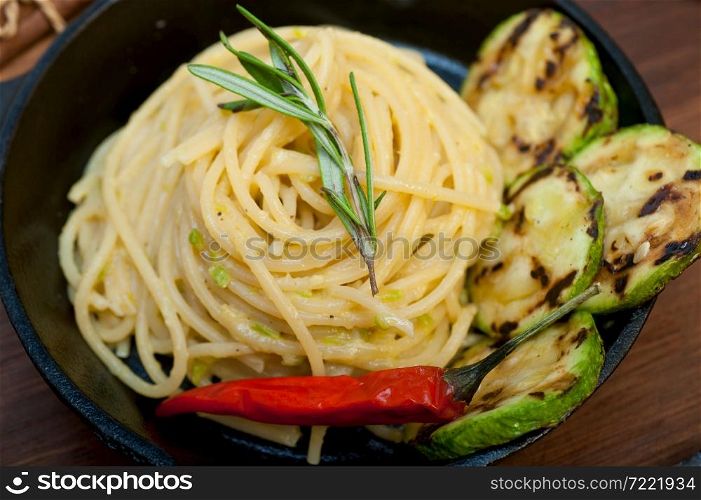 italian spaghetti pasta with zucchini sauce on iron skillet over wood board