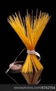 Italian spaghetti pastawith tape meter over black closeup