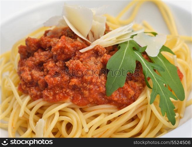 Italian spaghetti topped with bolognaise, or bolognese, sauce with tomatoes, meat and cheese on a plain white plate