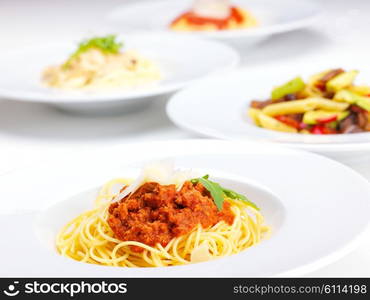 Italian spaghetti topped with bolognaise, or bolognese, sauce with tomatoes, meat and cheese on a plain white plate