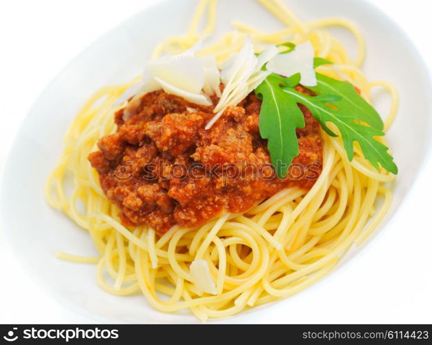 Italian spaghetti topped with bolognaise, or bolognese, sauce with tomatoes, meat and cheese on a plain white plate