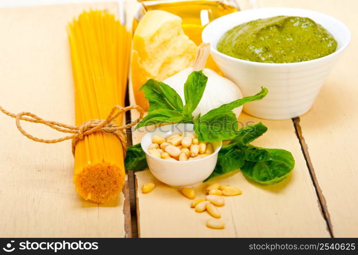 Italian traditional basil pesto pasta ingredients parmesan cheese pine nuts extra virgin olive oil garlic on a rustic table