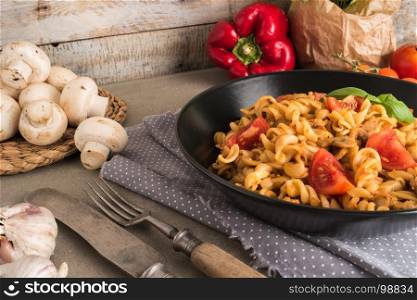 Italian wholemeal pasta with tuna, mushrooms and basil. Fresh pasta with tuna and tomato sauce on old wooden background. Italian cuisine concept.