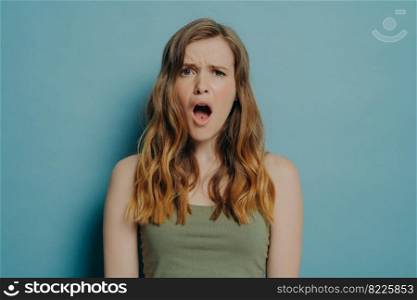 Its awful. Young displeased woman with slightly wavy hair looking at camera with dissatisfied shocked face expression and open mouth, unhappy female seeing something ugly and terrible in front of her. Young displeased woman with dissatisfied face expression and open mouth seeing something ugly