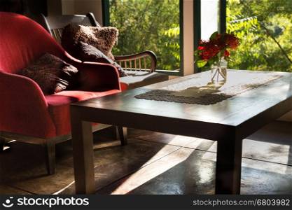 ixora flower in vase, wood table and chair in living room near window with garden view