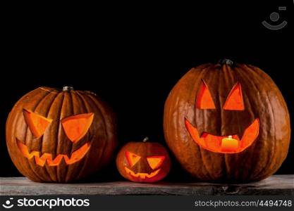 Jack o lanterns Halloween pumpkins. Thre Jack o lanterns halloween pumpkins on wooden table isolated on black background