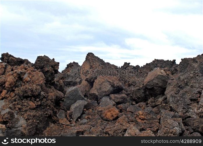Jagged volcanic basalt rocks against overcast sky.