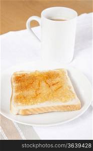 Jam on slice of bread with cup of coffee