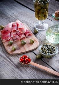 Jamon with capers and olives on the wooden board