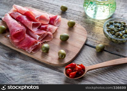 Jamon with capers and olives on the wooden board