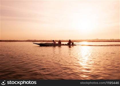 JAN 13, 2019 Udonthani, Thailand - Thai long tail boat with tourist in peaceful Nong Harn lake, Udonthani - Thailand. Wooden boat under warm beautiful sunrise sky over red lotus lake.