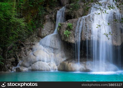 Jangle landscape with flowing turquoise water of Erawan cascade waterfall at deep tropical rain forest. National Park Kanchanaburi, Thailand