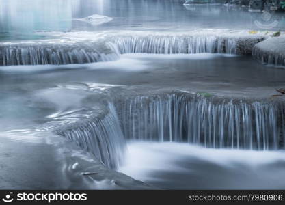 Jangle landscape with flowing turquoise water of Erawan cascade waterfall at deep tropical rain forest. National Park Kanchanaburi, Thailand