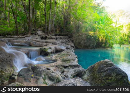 Jangle landscape with flowing turquoise water of Erawan cascade waterfall at deep tropical rain forest. National Park Kanchanaburi, Thailand