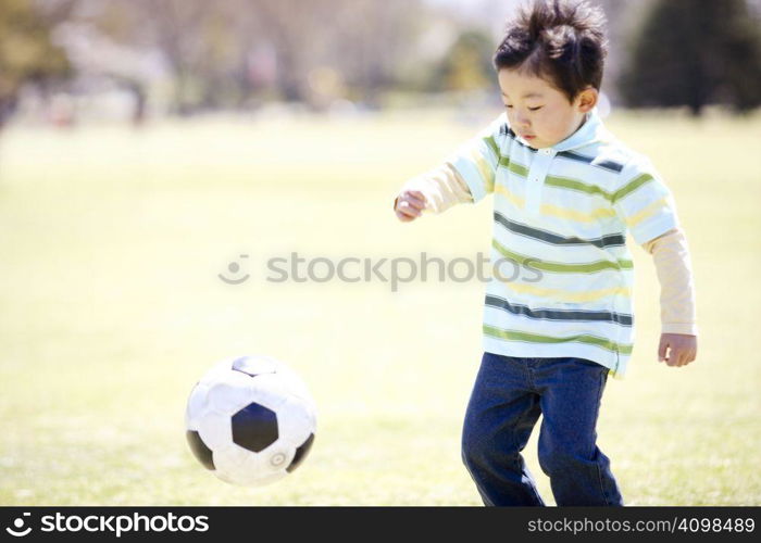 Japanese boy playing soccer in the park