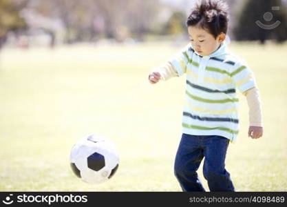 Japanese boy playing soccer in the park