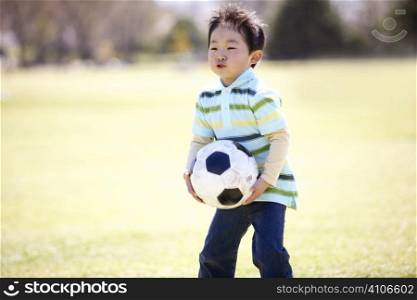 Japanese boy playing soccer in the park