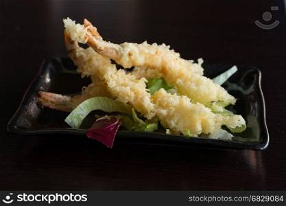 Japanese Cuisine - Tempura Shrimps (Deep Fried Shrimps) with sauce and vegetables on a black plate. Black background,shallow depth of field.