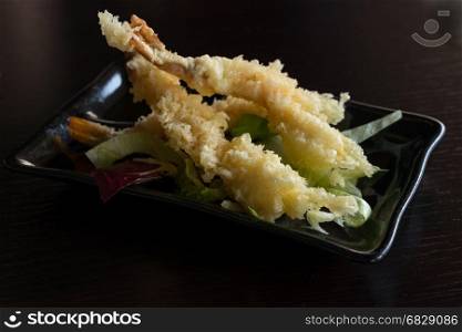 Japanese Cuisine - Tempura Shrimps (Deep Fried Shrimps) with sauce and vegetables on a black plate. Black background,shallow depth of field