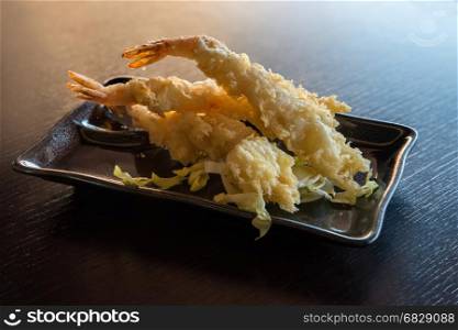 Japanese Cuisine - Tempura Shrimps (Deep Fried Shrimps) with sauce and vegetables on a black plate.