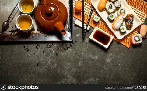 Japanese food. Rolls , sushi and hot tea. On the stone table.. Japanese food. Rolls , sushi and hot tea.