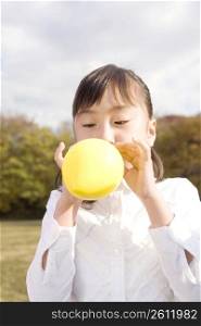 Japanese girl blowing up a balloon