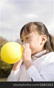 Japanese girl blowing up a balloon