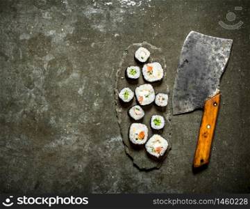 Japanese rolls with a hatchet for cutting. On the stone table.. Japanese rolls with a hatchet for cutting.