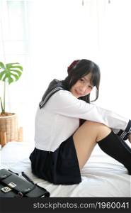 japanese school girl sitting on bedroom in white tone