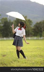 Japanese school with umbrella on rain in countryside with grass mountain and tree