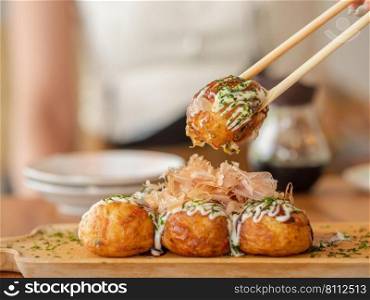 Japanese snack, takoyaki ball. Focus on the takoyaki ball on the chopsticks. Typical Japanese snack.