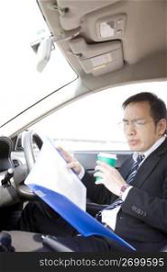 Japanese worker checking a document in a car